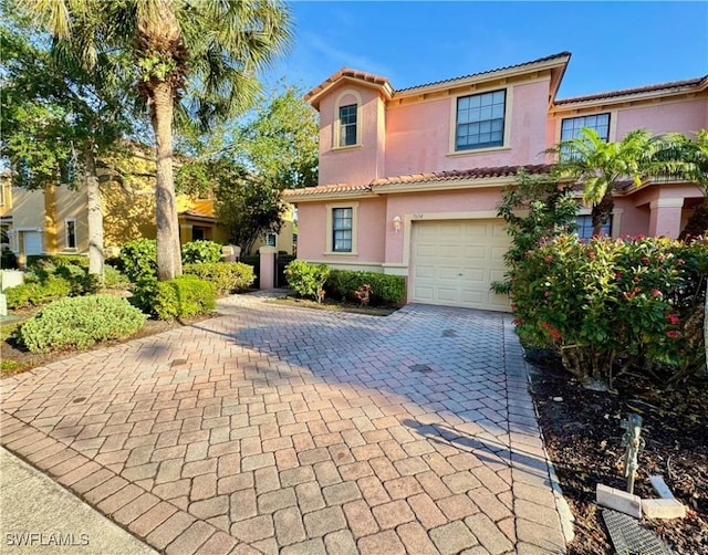mediterranean / spanish-style house with stucco siding, a garage, decorative driveway, and a tiled roof