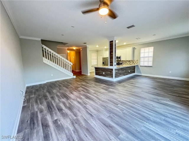 unfurnished living room with crown molding, baseboards, a ceiling fan, stairs, and dark wood-type flooring