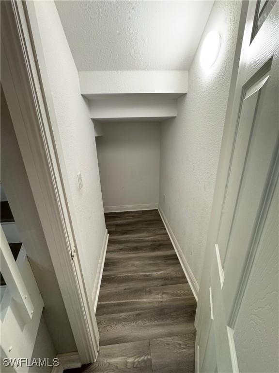 stairs with a textured wall, wood finished floors, and baseboards