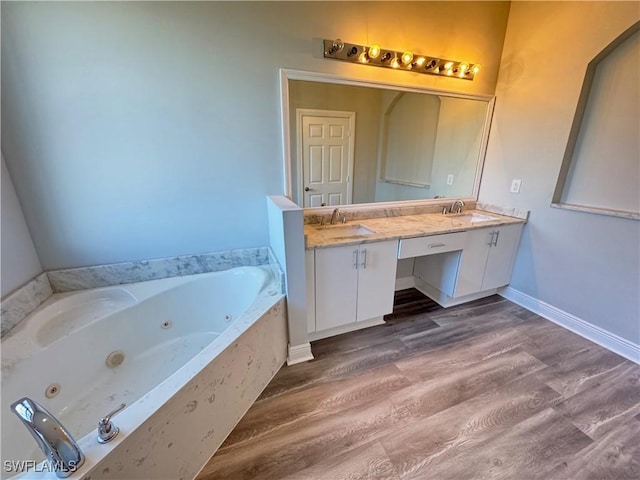 full bath with wood finished floors, double vanity, a tub with jets, and baseboards