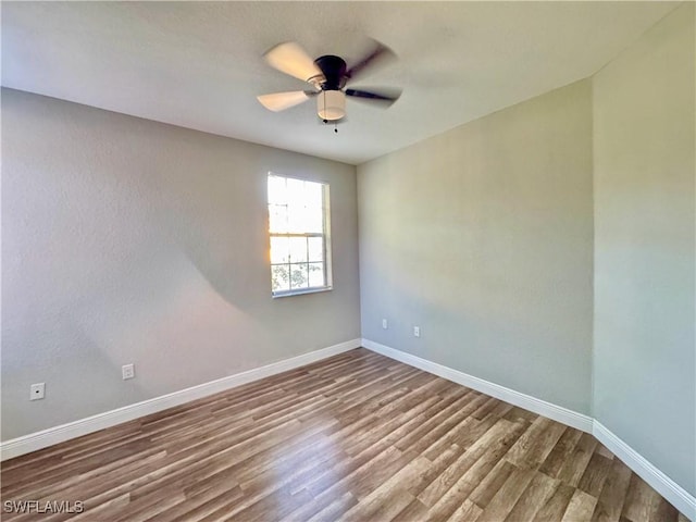 spare room featuring wood finished floors, baseboards, and ceiling fan
