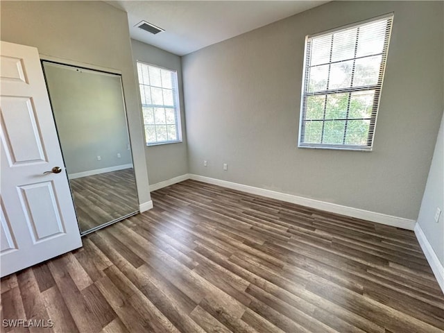 unfurnished bedroom with dark wood finished floors, baseboards, and a closet