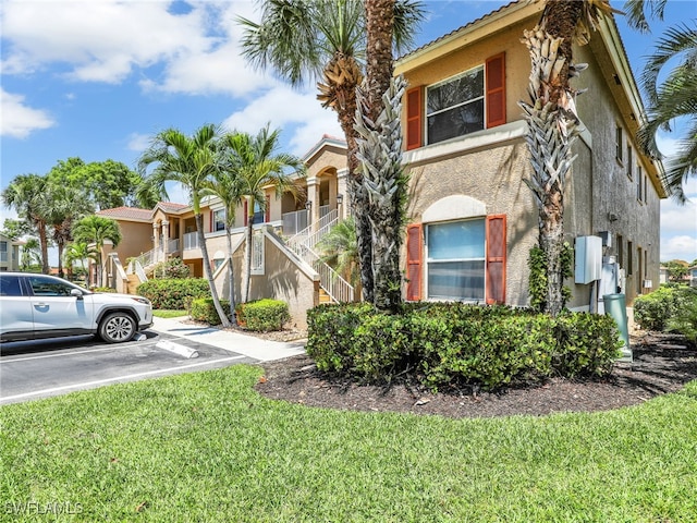 6670 Huntington Lakes Cir Unit 104, Naples, FL 34119 - view of property with stairs, uncovered parking, stucco siding, and a front yard