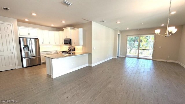 986 Enbrook Loop, Naples, FL 34114 - kitchen featuring stainless steel appliances, open floor plan, wood finished floors, a chandelier, and a peninsula