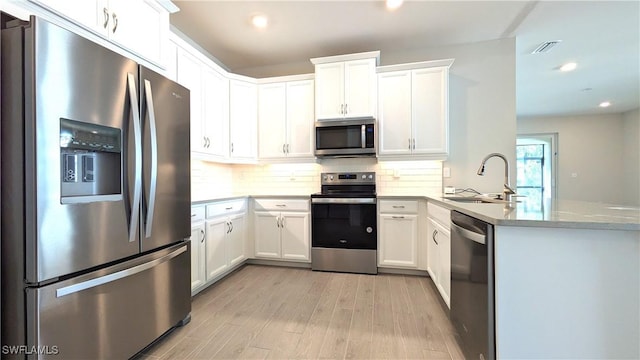 986 Enbrook Loop, Naples, FL 34114 - kitchen featuring stainless steel appliances, a sink, light wood-style flooring, a peninsula, and tasteful backsplash