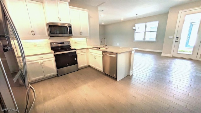 986 Enbrook Loop, Naples, FL 34114 - kitchen featuring stainless steel appliances, a sink, a peninsula, light wood-style floors, and tasteful backsplash