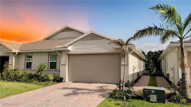 986 Enbrook Loop, Naples, FL 34114 - view of front of property featuring a garage, decorative driveway, board and batten siding, and a tile roof