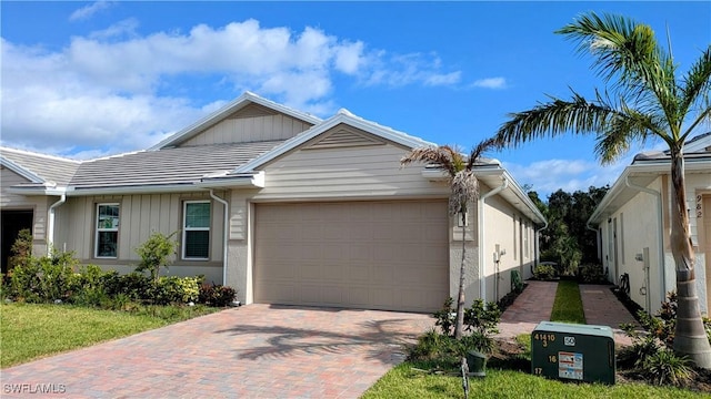 986 Enbrook Loop, Naples, FL 34114 - view of front of house featuring a garage, decorative driveway, board and batten siding, and a tiled roof