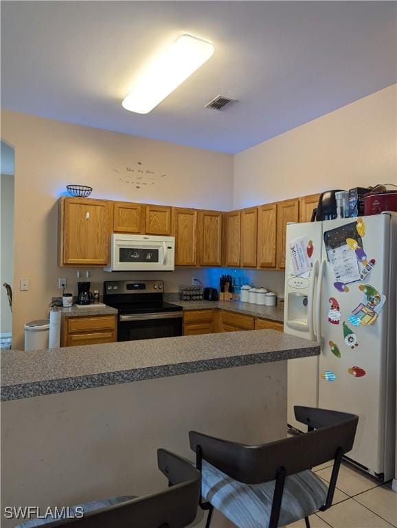 2543 Nature Pointe Loop, Fort Myers, FL 33905 - kitchen featuring white appliances, light tile patterned floors, a breakfast bar area, and brown cabinetry