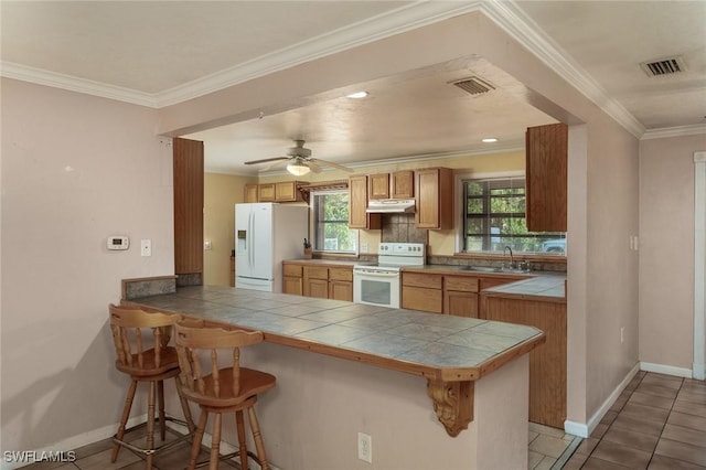 7384 Coon Rd, North Fort Myers, FL 33917 - kitchen featuring white appliances, tile counters, a peninsula, a kitchen breakfast bar, and baseboards