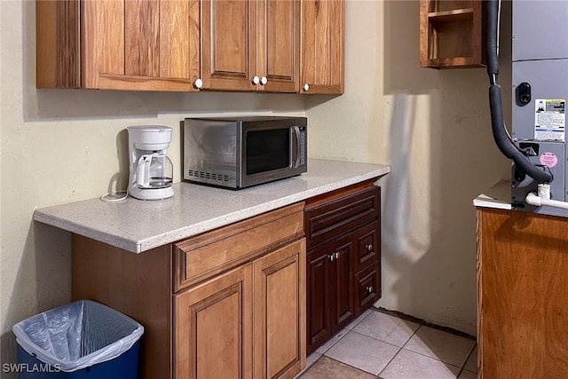 7384 Coon Rd, North Fort Myers, FL 33917 - kitchen with stainless steel microwave, light countertops, light tile patterned floors, and brown cabinetry