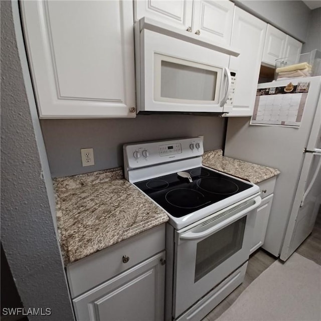 2925 Winkler Ave Unit 906, Fort Myers, FL 33916 - kitchen with white appliances, white cabinets, light wood-style flooring, and light stone countertops