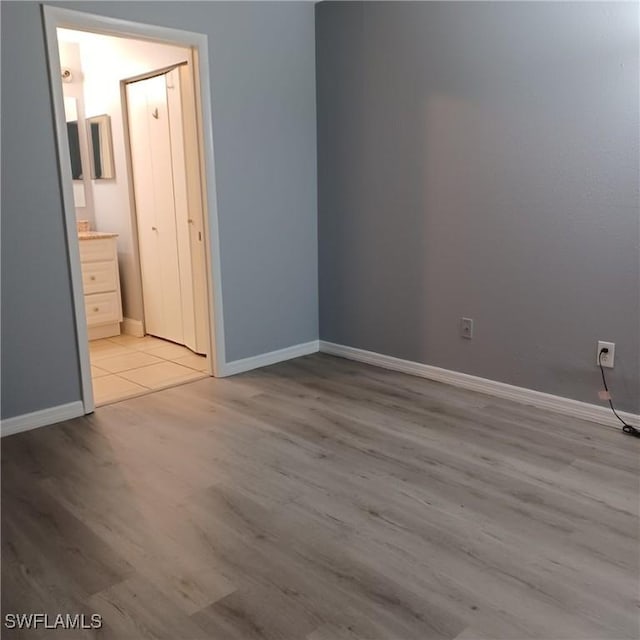 2925 Winkler Ave Unit 906, Fort Myers, FL 33916 - unfurnished bedroom with light wood finished floors, baseboards, and ensuite bath