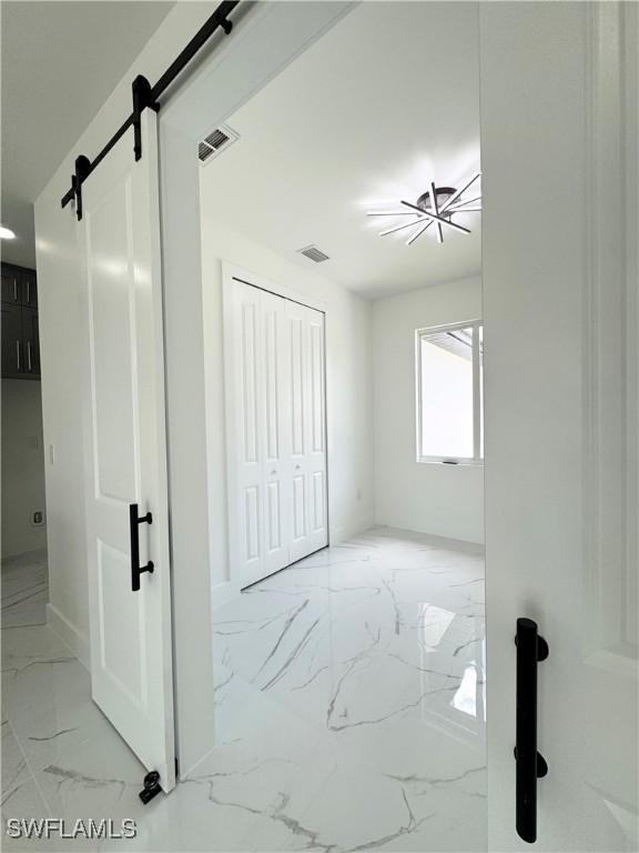 1010 Euclid Ave, Lehigh Acres, FL 33972 - unfurnished bedroom featuring light marble finish flooring, a barn door, baseboards, and a closet