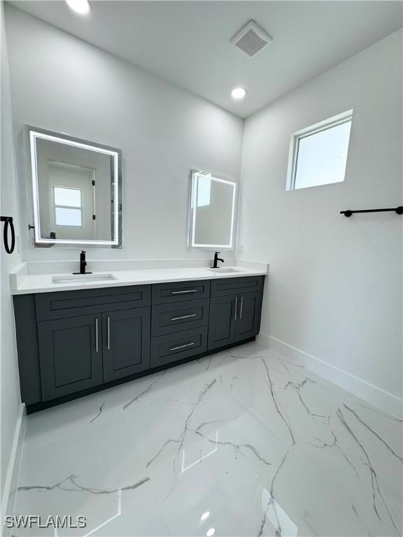 1010 Euclid Ave, Lehigh Acres, FL 33972 - full bath featuring baseboards, double vanity, marble look tiles, and recessed lighting