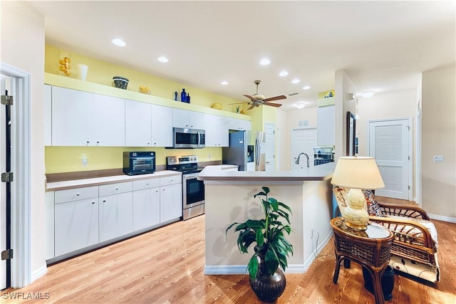 19977 Lake Vista Cir Unit 17A, Lehigh Acres, FL 33936 - kitchen with appliances with stainless steel finishes, light wood finished floors, white cabinets, a ceiling fan, and recessed lighting