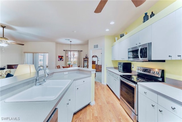 19977 Lake Vista Cir Unit 17A, Lehigh Acres, FL 33936 - kitchen with appliances with stainless steel finishes, ceiling fan, light countertops, light wood finished floors, and a sink