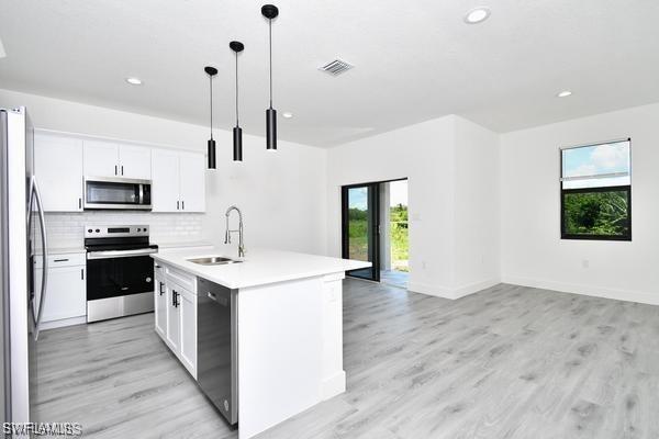 8304 Lena Ct, Labelle, FL 33935 - kitchen with stainless steel appliances, a sink, open floor plan, light countertops, and tasteful backsplash