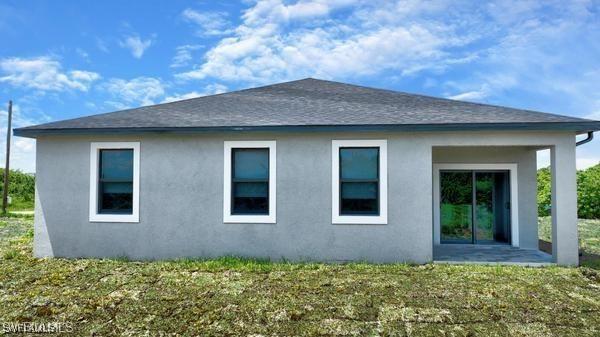 8304 Lena Ct, Labelle, FL 33935 - back of property with stucco siding and a lawn
