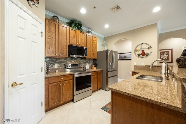 14746 Calusa Palms Dr Unit 102, Fort Myers, FL 33919 - kitchen with appliances with stainless steel finishes, a sink, crown molding, brown cabinets, and backsplash