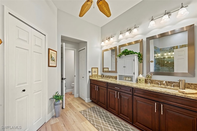 10016 Majestic Ave, Fort Myers, FL 33913 - bathroom with a ceiling fan, tiled shower, toilet, wood finished floors, and double vanity