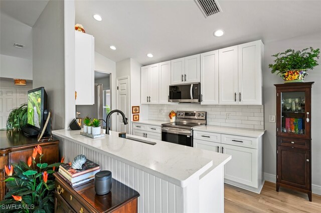 10016 Majestic Ave, Fort Myers, FL 33913 - kitchen with appliances with stainless steel finishes, a sink, backsplash, light wood-style floors, and a peninsula
