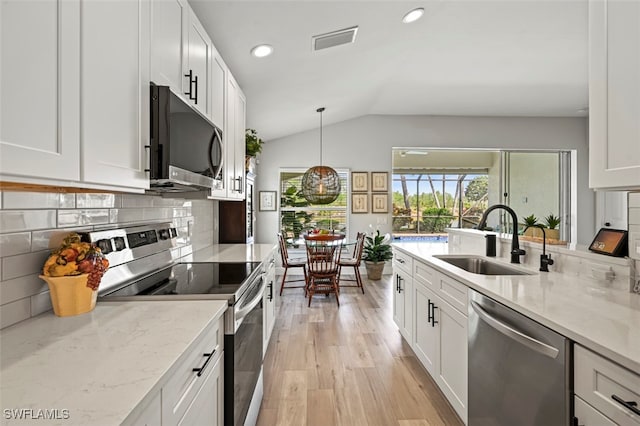 10016 Majestic Ave, Fort Myers, FL 33913 - kitchen with stainless steel appliances, a sink, lofted ceiling, light wood-style flooring, and white cabinetry