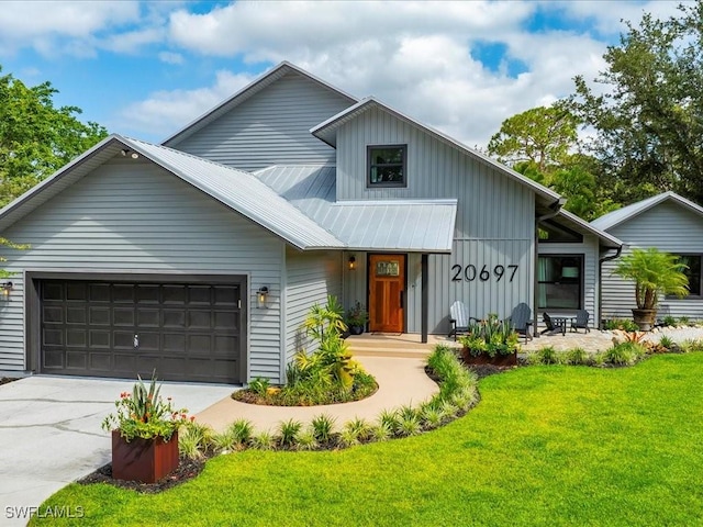 20697 Charing Cross Cir, Estero, FL 33928 - view of front facade featuring board and batten siding, a front lawn, a garage, concrete driveway, and metal roof
