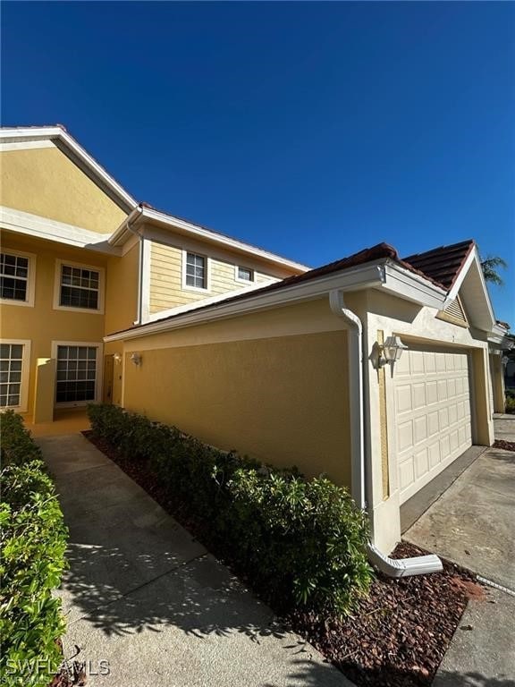13000 Sandy Key Bnd Unit 3202, North Fort Myers, FL 33903 - view of side of property featuring stucco siding, a garage, and concrete driveway