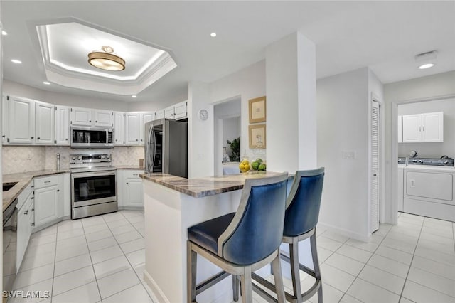 591 Audubon Blvd Unit B202, Naples, FL 34110 - kitchen with appliances with stainless steel finishes, light tile patterned floors, a breakfast bar area, tasteful backsplash, and light stone countertops