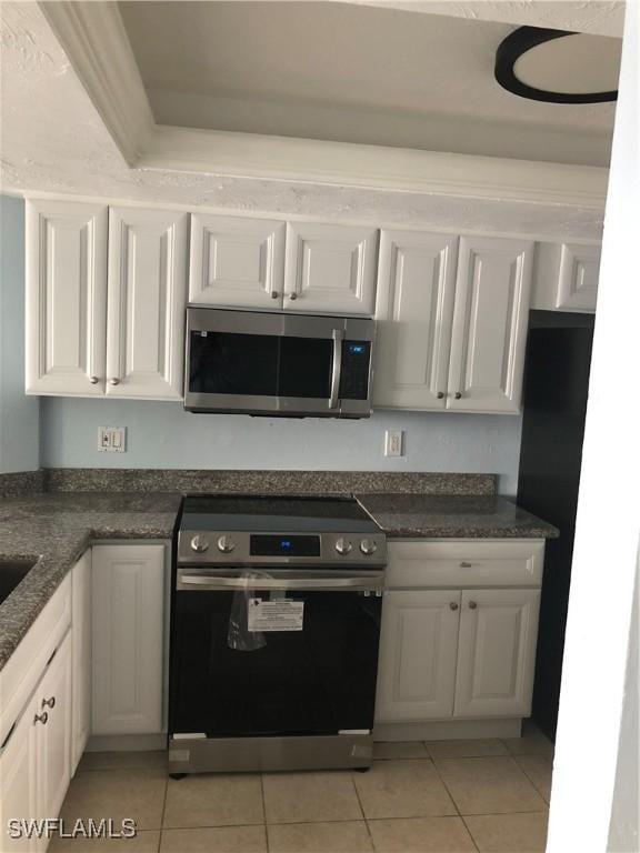 4510 N Key Dr Unit 302, North Fort Myers, FL 33903 - kitchen featuring appliances with stainless steel finishes, light tile patterned floors, white cabinets, and dark countertops