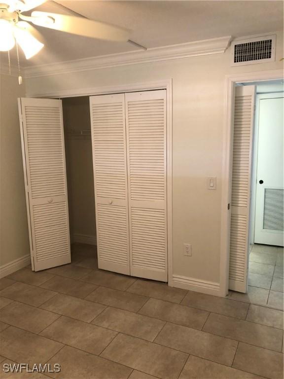4510 N Key Dr Unit 302, North Fort Myers, FL 33903 - unfurnished bedroom featuring crown molding, a closet, light tile patterned flooring, baseboards, and a ceiling fan