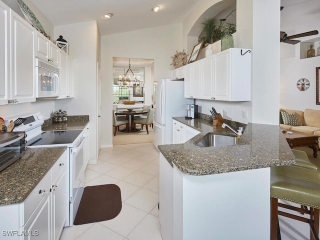 26986 Montego Pointe Ct Unit 202, Bonita Springs, FL 34134 - kitchen featuring white appliances, a sink, white cabinetry, light tile patterned floors, and a peninsula