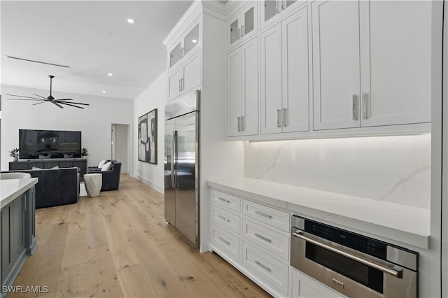 24721 Bay Bean Ct, Bonita Springs, FL 34134 - kitchen with appliances with stainless steel finishes, ceiling fan, light stone counters, recessed lighting, and light wood finished floors