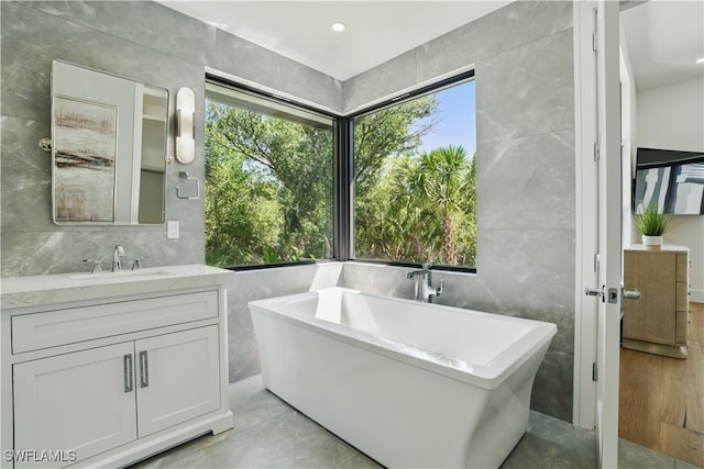24721 Bay Bean Ct, Bonita Springs, FL 34134 - bathroom featuring tile walls, plenty of natural light, a freestanding tub, and vanity