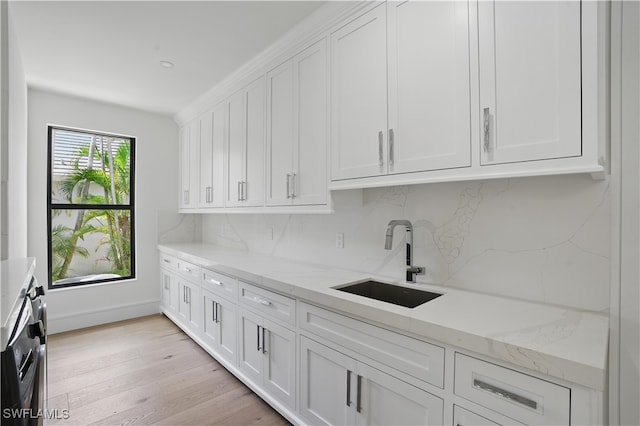 24721 Bay Bean Ct, Bonita Springs, FL 34134 - kitchen with a sink, backsplash, white cabinets, light wood-style floors, and light stone countertops