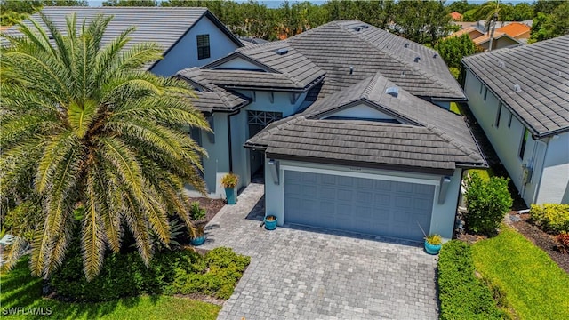 10138 Palazzo Dr, Naples, FL 34119 - view of front facade with an attached garage, decorative driveway, a tiled roof, and stucco siding