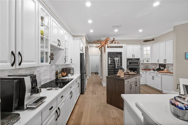12501 Walden Run Dr, Fort Myers, FL 33913 - kitchen with black appliances, crown molding, white cabinetry, a center island, and tasteful backsplash