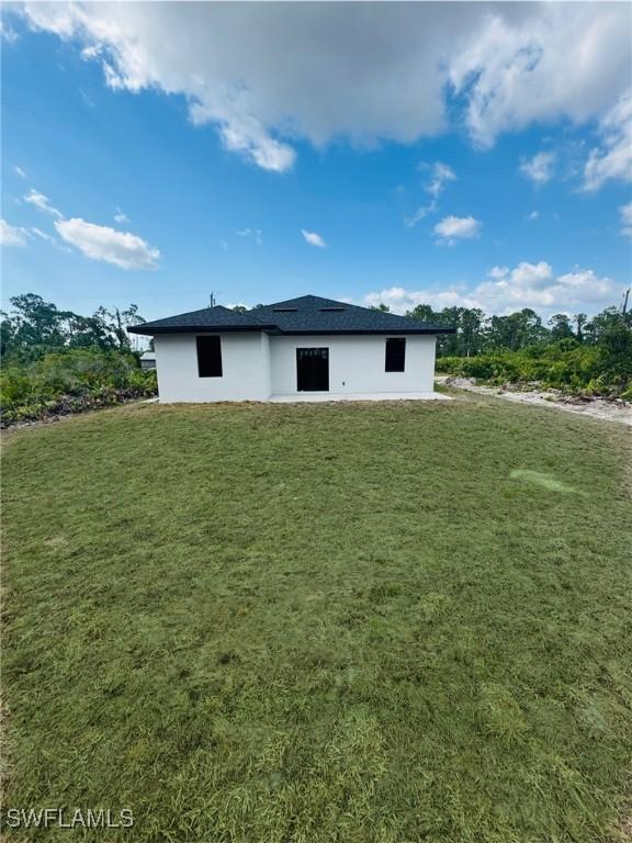 2917 50th St W, Lehigh Acres, FL 33971 - rear view of property with a yard and stucco siding