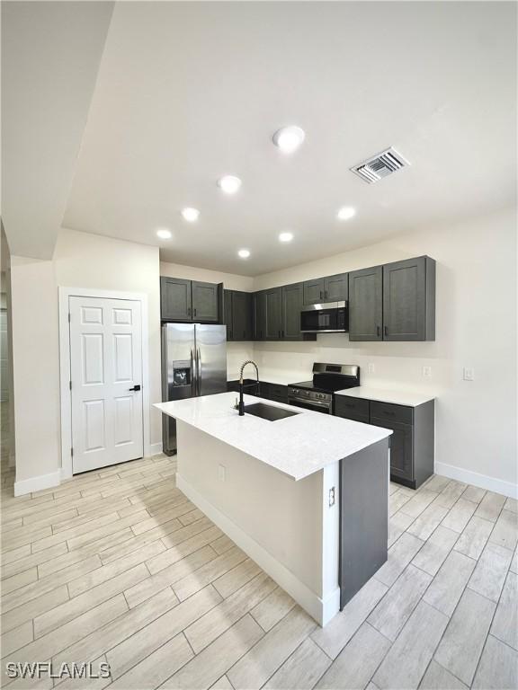 2917 50th St W, Lehigh Acres, FL 33971 - kitchen with appliances with stainless steel finishes, a sink, wood tiled floors, light countertops, and baseboards