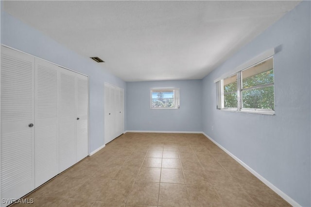 198 Joel Blvd Unit 5, Lehigh Acres, FL 33936 - unfurnished bedroom with two closets, light tile patterned flooring, and baseboards