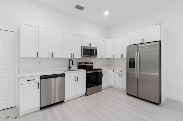 5015 Placid Ln, Labelle, FL 33935 - kitchen with stainless steel appliances, a sink, light countertops, light wood-type flooring, and white cabinetry