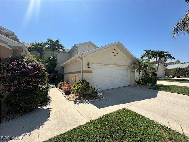 4219 Tequesta Dr, Estero, FL 33928 - view of side of property with an attached garage, concrete driveway, and stucco siding