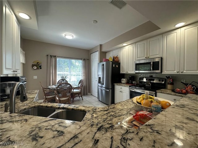 4219 Tequesta Dr, Estero, FL 33928 - kitchen featuring appliances with stainless steel finishes, light stone countertops, a sink, and white cabinets