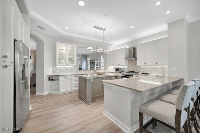 2839 Tiburon Blvd E Unit 102, Naples, FL 34109 - kitchen featuring wall chimney exhaust hood, appliances with stainless steel finishes, a peninsula, backsplash, and recessed lighting