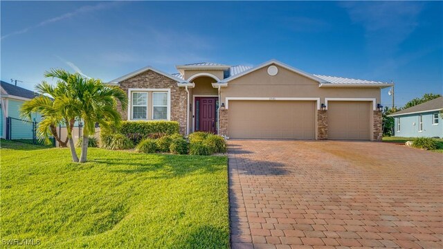 2541 SW 32nd Ln, Cape Coral, FL 33914 - view of front of property with decorative driveway, a front lawn, an attached garage, stucco siding, and stone siding