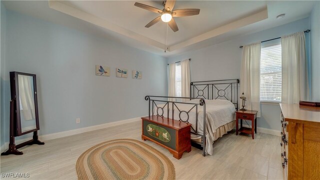 2541 SW 32nd Ln, Cape Coral, FL 33914 - bedroom featuring a raised ceiling, baseboards, light wood finished floors, and ceiling fan