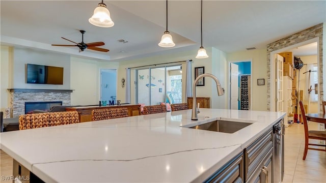 2541 SW 32nd Ln, Cape Coral, FL 33914 - kitchen with a sink, light stone countertops, a ceiling fan, a fireplace, and pendant lighting