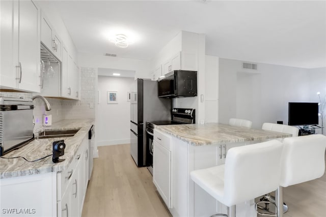 3905 Del Prado Blvd S Unit D-101, Cape Coral, FL 33904 - kitchen with stainless steel appliances, a sink, a kitchen breakfast bar, light wood-style floors, and white cabinetry