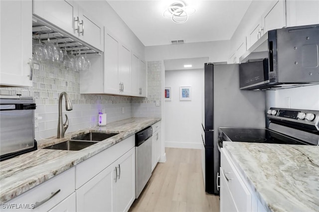 3905 Del Prado Blvd S Unit D-101, Cape Coral, FL 33904 - kitchen with appliances with stainless steel finishes, a sink, white cabinets, decorative backsplash, and light wood-type flooring